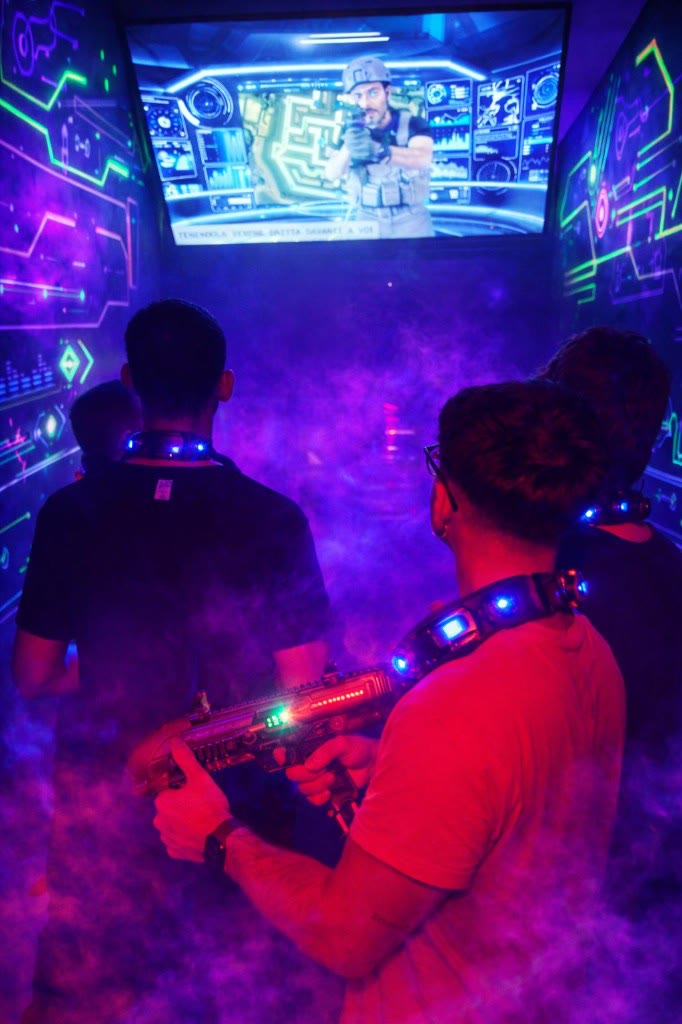 Briefing automatico Laser Game: giocatori con sensoristica LED davanti allo schermo missione