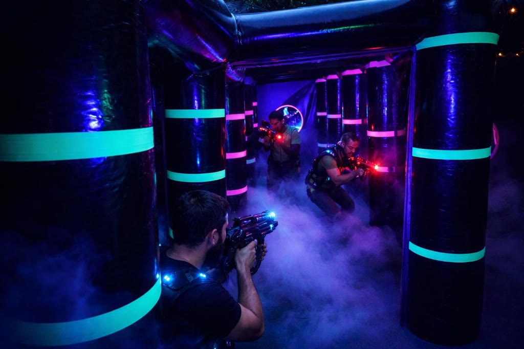 Arena laser immersiva con fumo UV e giocatori in azione — il wow c’è, ma il cantiere tradizionale resta un ostacolo